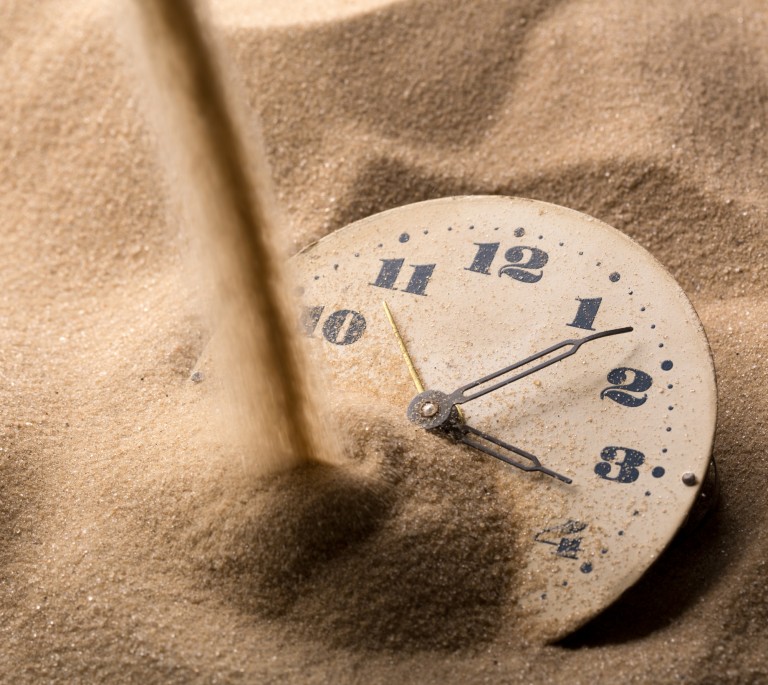 Face of clock in sand